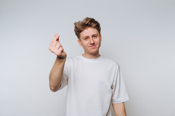 Fototapeta premium Young man making a gesture with his hand while standing against a plain background indoors