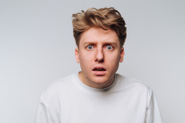Fototapeta premium Man shows surprised expression against plain background during indoor session