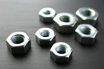 Metal hex nuts on dark wooden table, closeup