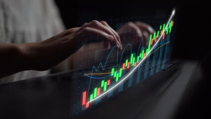 Close-up view of hands typing on a keyboard with an overlaid financial graph on a screen, illustrating stock market trends and data analysis in a modern workspace. Copula