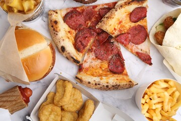Different delicious fast food on white marble table, flat lay