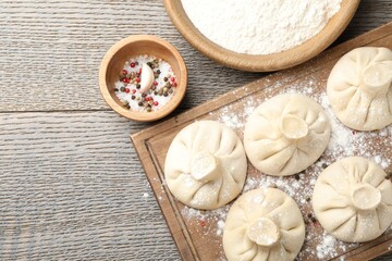 Uncooked khinkalis (dumplings) and spices on wooden table, flat lay. Space for text