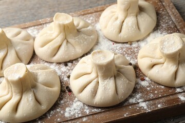 Uncooked khinkalis (dumplings) on wooden table, closeup