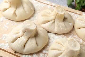 Uncooked khinkalis (dumplings) on wooden board, closeup