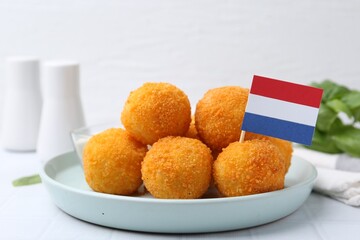 Delicious fried croquette balls and flag of Netherlands on light table, closeup
