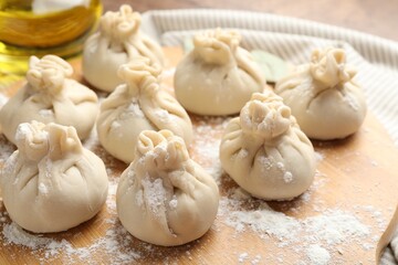Uncooked khinkalis (dumplings) with flour on table, closeup