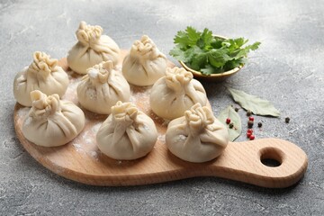 Uncooked khinkalis (dumplings) with peppercorns, flour, parsley and bay leaves on grey table