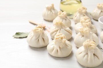 Uncooked khinkalis (dumplings) and spices on white wooden table, closeup