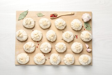 Uncooked khinkalis (dumplings) and spices on white wooden table, top view