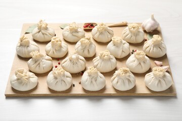 Uncooked khinkalis (dumplings) and spices on white wooden table, closeup