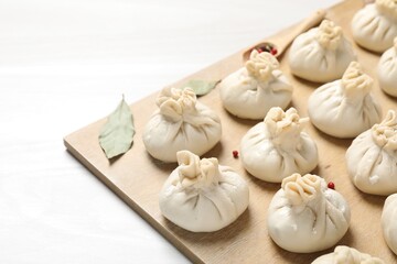 Uncooked khinkalis (dumplings) and spices on white wooden table, closeup
