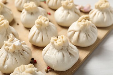 Uncooked khinkalis (dumplings) and spices on white table, closeup