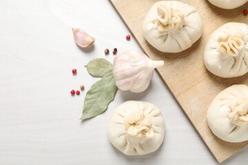Uncooked khinkalis (dumplings) and spices on white wooden table, flat lay. Space for text