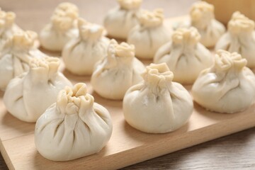 Uncooked khinkalis (dumplings) on wooden table, closeup