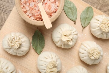 Uncooked khinkalis (dumplings) and spices on wooden table, top view