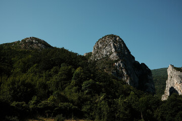 Majestic rocky peaks rising above dense green forest under a clear blue sky in Stara Planina, Serbia