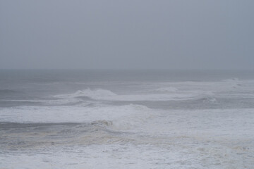 Powerful waves surging against rocky coastline, dark clouds overhead generating intense, brooding seascape mood