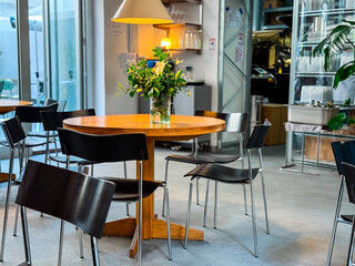 Cafe interior with wooden tables and glass shelves on wall. Urban lifestyle, hospitality, and social culture.