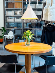 Round wooden table with vase of flowers inside cafe. Interior design, lifestyle, and social gathering.