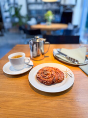 Cup of coffee with sweet pastry on wooden table. Breakfast, indulgence, gastronomy, and cafe culture.