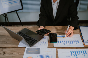 Asian businesswoman using calculator and working on laptop computer at modern office, business and finance concept