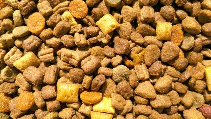 Textured background close-up of dry pet food croquettes and treats for pets, cats, or dogs