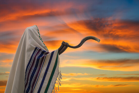 Jewish man wearing a tallit prayer shawl standing beneath a dramatic sky.