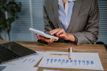 An Asian businesswoman accountant calculates invoices, taxes, interest, loans using a calculator,working online to guide clients through financial planning ensure a smooth loan process for success