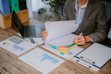 Image of young Asian business woman working working in Stacks of paper files for searching and...
