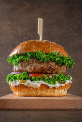 Juicy hamburger on a stand on a brown background