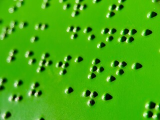 Macro image of Braille writing on a textured green surface, symbolizing accessibility, communication, and inclusivity.