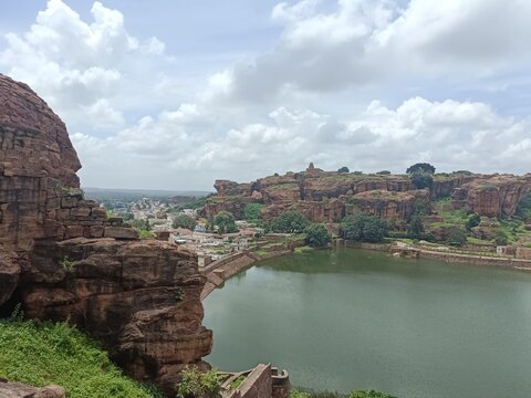 Scenic view of Badami rock formations and lake during a cloudy afternoon, showcasing nature's beauty and historical significance