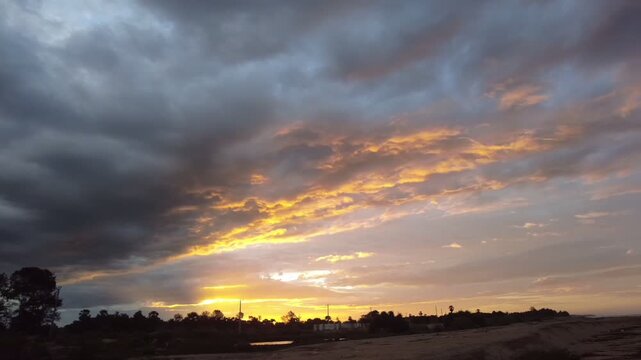 Evening seascape captured on 13.06.2025 in Ninthavur, Ampara District. The sunset glows through dark clouds, painting the sky with golden hues over the calm sea.