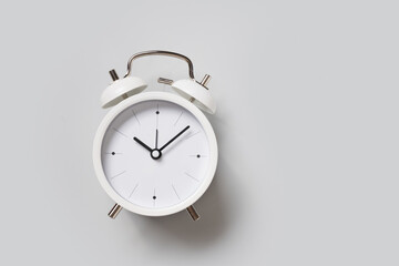 White alarm clock on gray background. View from above.
