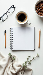 Minimalist overhead shot of notebook, coffee, and accessories on white table