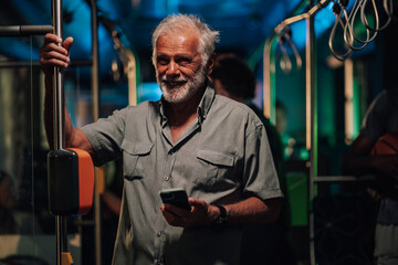 Senior man using smartphone on public transport at night
