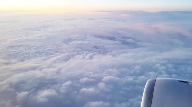 Airplane flying over beautiful clouds at sunrise