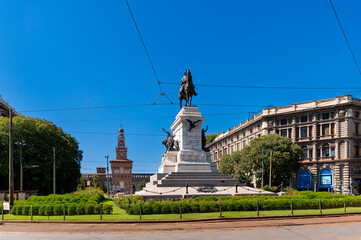 Majestic equestrian statue of Giuseppe Garibaldi in Milan&rsquo;s Piazza Cairoli, framed by lush greenery and historic architecture under a clear blue sky.