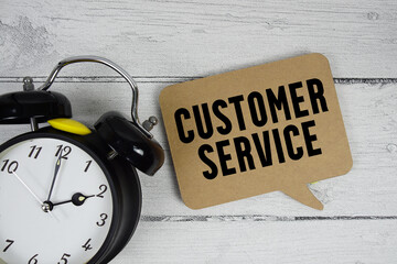 Customer service text with alarm clock on wooden background