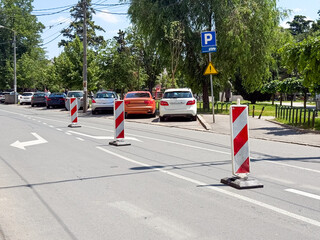 Street with parking cars and temporary traffic barriers. Concept of transport, infrastructure, and urban road safety.