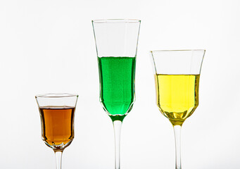 Three glasses filled with colorful alcoholic drinks on a white background, elegant barware, vibrant cocktails, party drinks, still life photography..