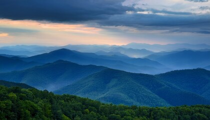 misty blue mountains stretch across the horizon under a dramatic cloudy sky with dense forested hills and lush greenery in the foreground at dawn or dusk