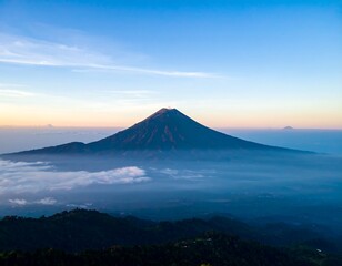 Volcanic peak rises above a cloud-shrouded landscape at sunrise