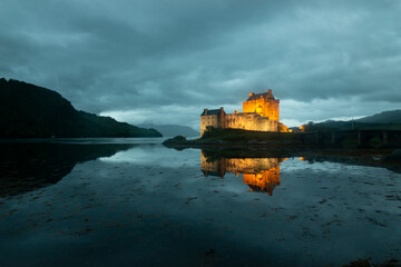 un chateau en lumiere en pleine nuit au milieu d'un lac avec son reflet, vue de nuit de Eilean...