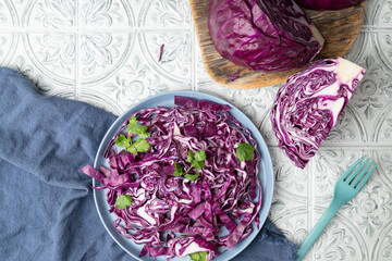 Raw, red cabbage salad with fresh green cilantro on a blue plate.