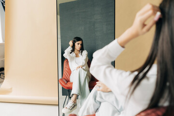A young woman model looks lovingly at her reflection in the mirror.