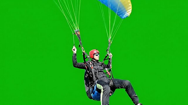 Person with parachute gliding against green screen background representing adventure, skydiving sports, outdoor extreme activity visuals, and promotional adventure content.