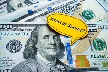 Money with the words invest or spend. Financial decision making.