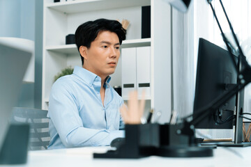 Fototapeta premium Serious smart businessman working on computer to check email with business project report, analyzing on market share's customer database in casual day at modern office in startup concept. Infobahn.