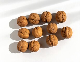 Walnuts arranged on a white surface with shadows